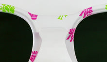 Cargar imagen en el visor de la galería, Detalle frontal de gafas de sol blancas con cristales oscuros y motivos falleros en rosa y verde de Peinetta Roja.