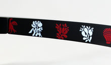 Cargar imagen en el visor de la galería, Gafas de sol falleras negras con cristales oscuros y dibujos tradicionales valencianos en rojo y blanco para fiestas falleras

